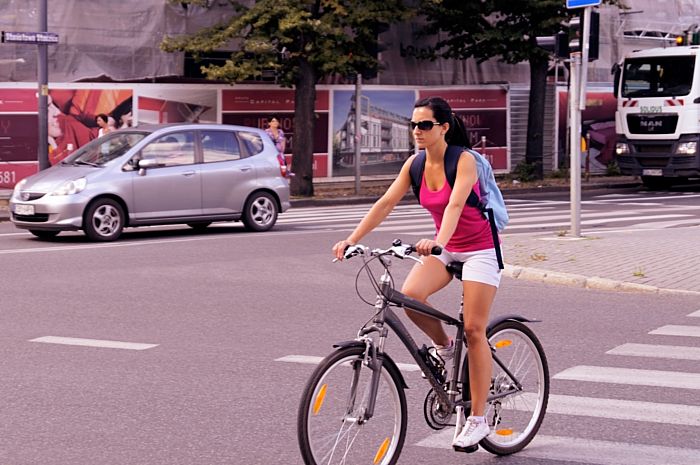 Bezaubernde Mountainbikfahrerin mit schickem funktionellem hellblauem Rucksack