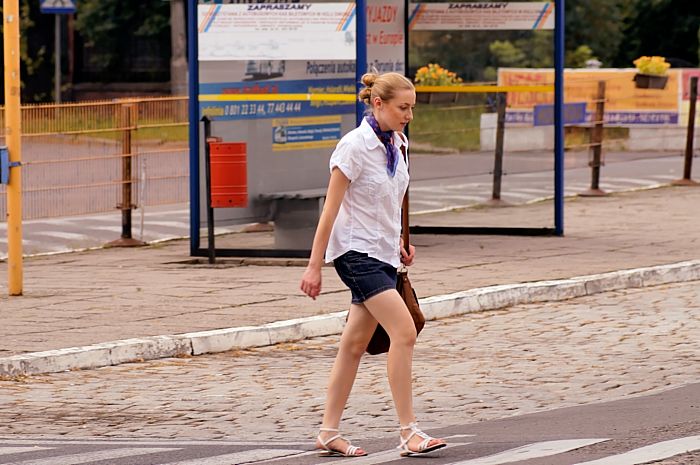 Bezauberndes Girl mit schickem Halstuch geht ueber Zebrastreifen